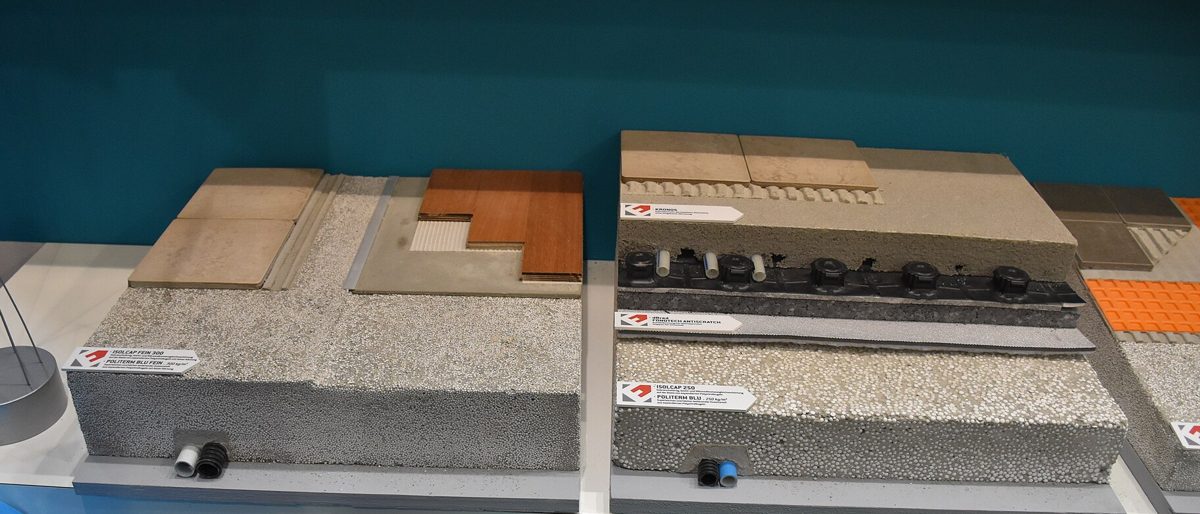 Cut-away samples of floor build-ups on a fair stand: insulation, screed and pipes under tile and wood flooring