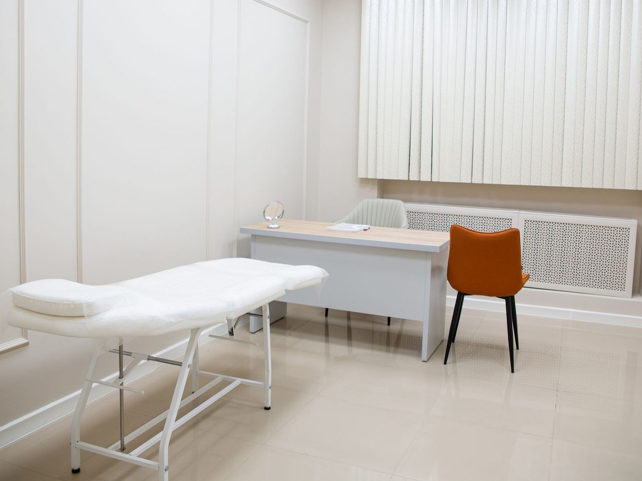 Examination room with a treatment bed, desk and pale floor