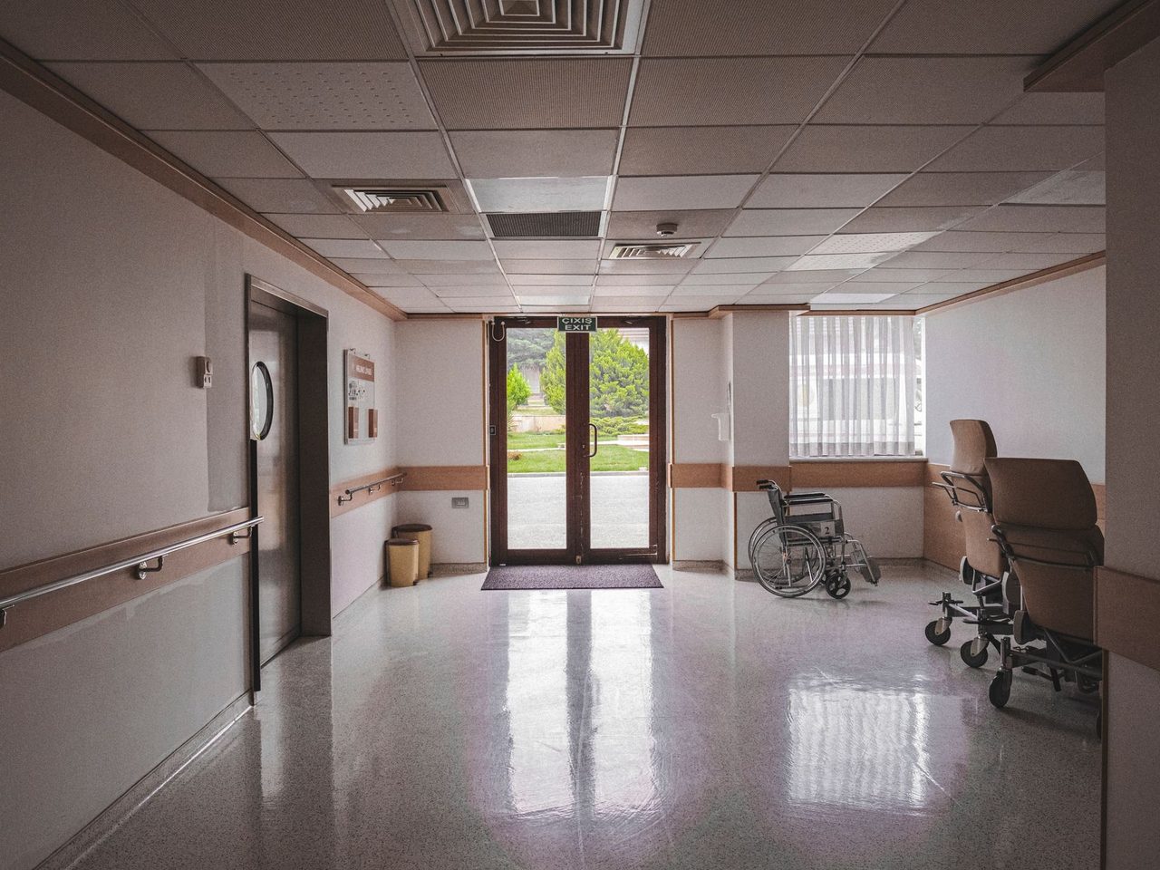 Hospital corridor with a wheelchair, handrails and a glossy floor