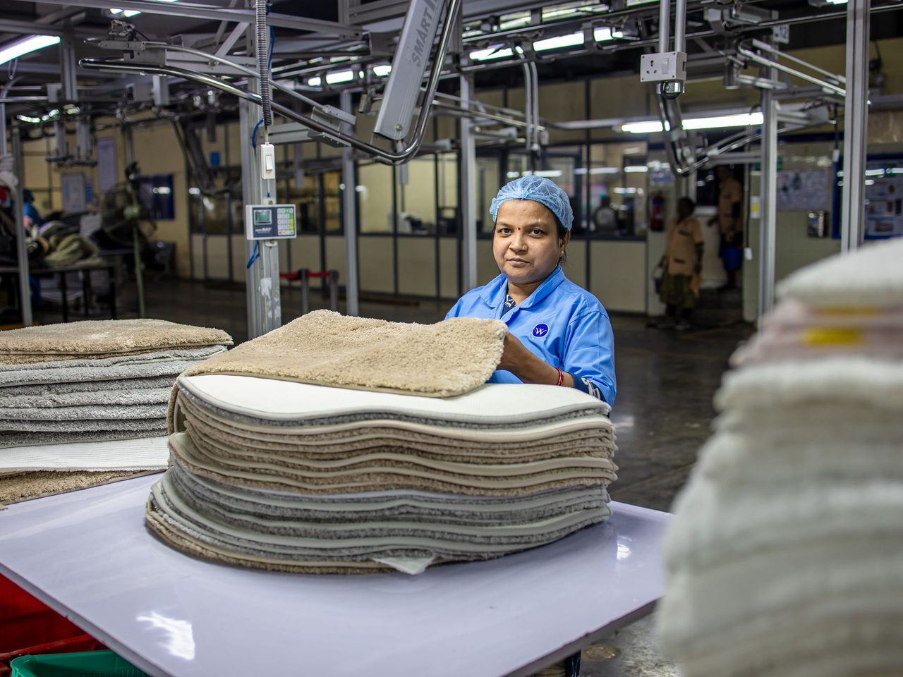 Factory worker handling stacks of textile tiles on a production line