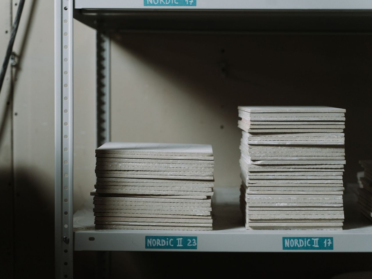 Stacks of square tiles on metal warehouse shelving
