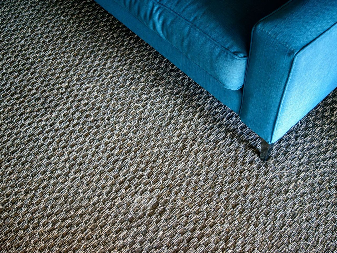 Blue sofa corner resting on a textured woven carpet