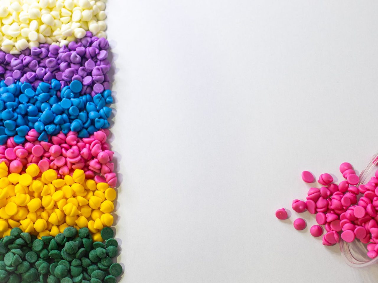 Rows of colored plastic pellets on a white background