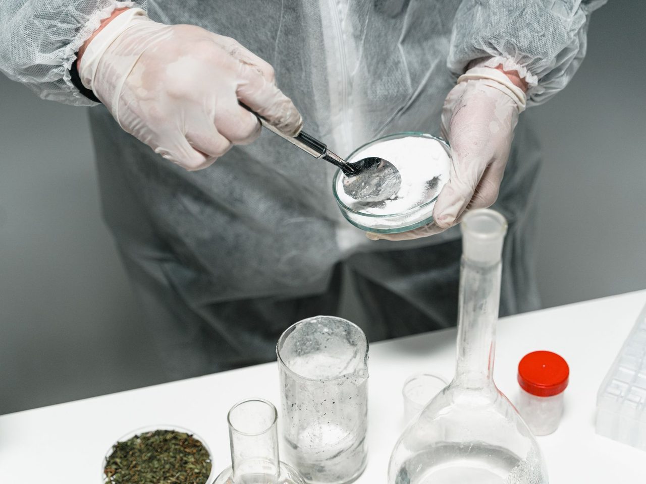 Scientist in protective gear handling a powder sample in a laboratory