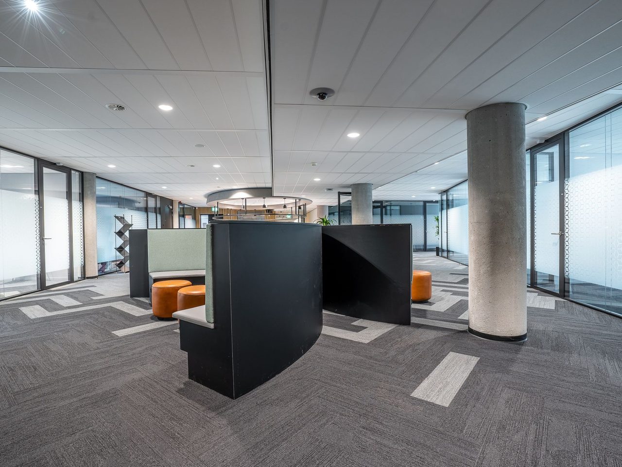Open office with carpet tile in a striped layout and a central column