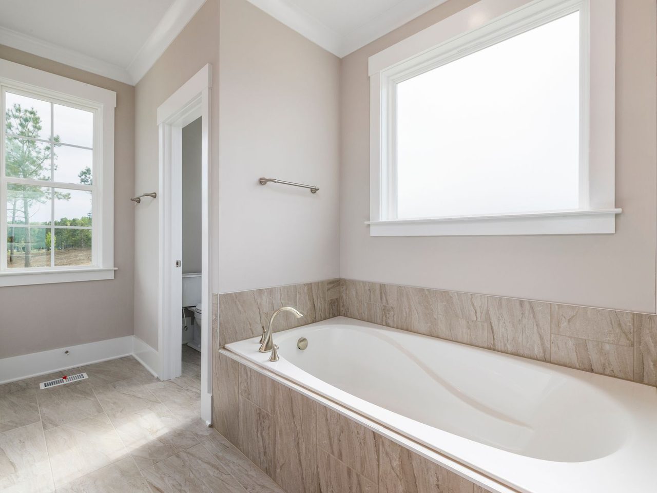 Built-in bathtub with a tiled surround next to a light wood-look plank floor