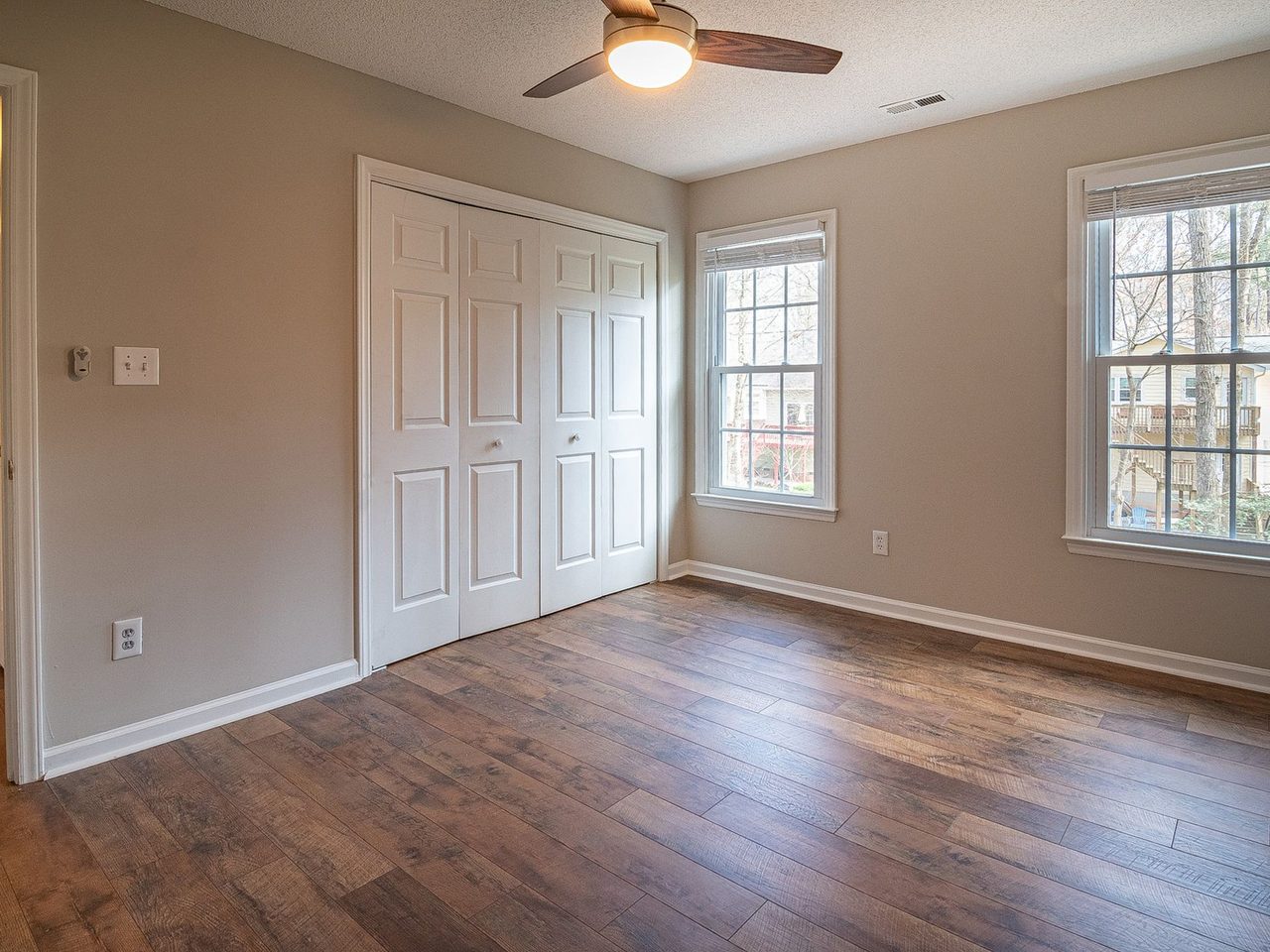 Empty room with a dark plank floor, a closet and windows