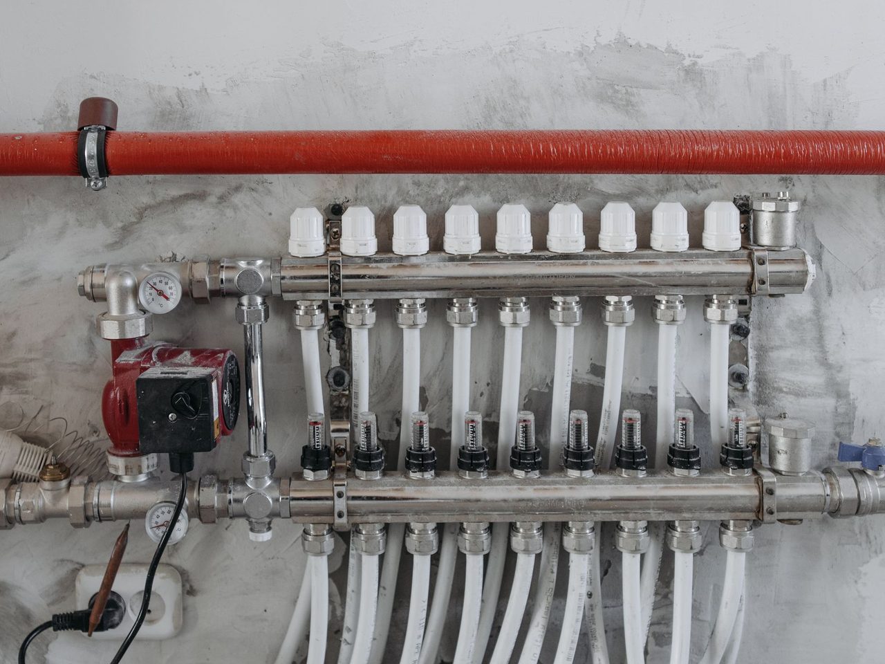 Heating manifold with a row of valves, pipes and pressure gauges on a wall
