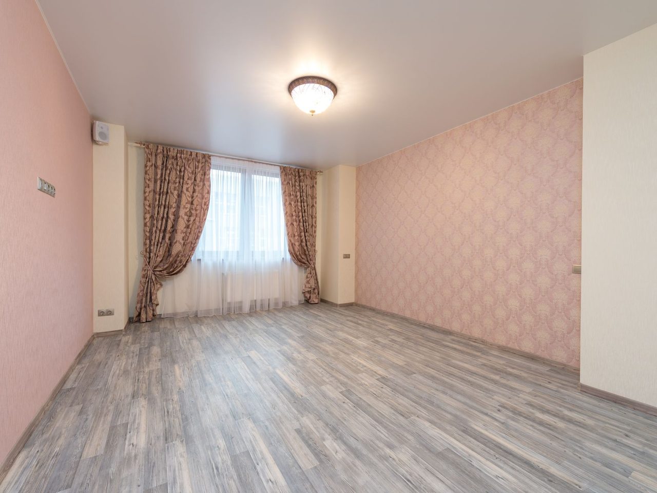 Empty room with a gray plank floor, pink walls and curtains