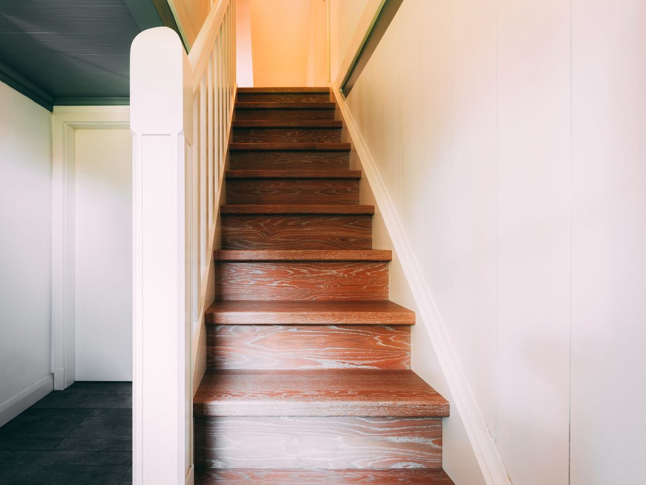 Narrow wooden staircase with a white stringer rising to an upper floor