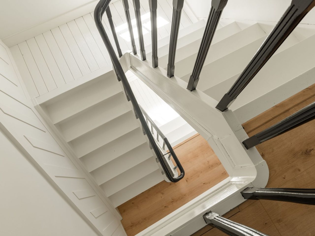 Interior staircase with light wood treads and dark metal railings seen from above