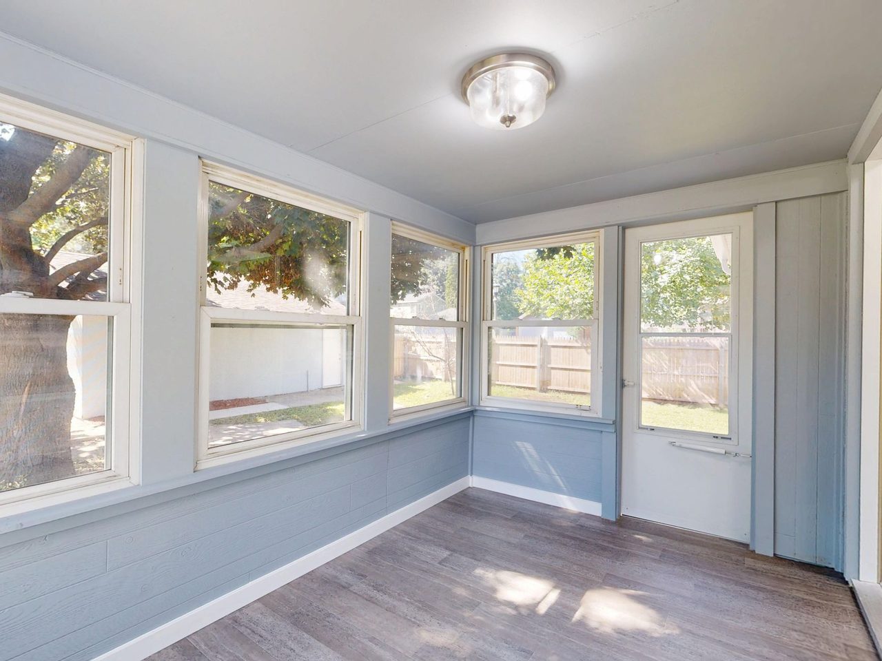 Sunroom with windows on three sides and a wood-look plank floor