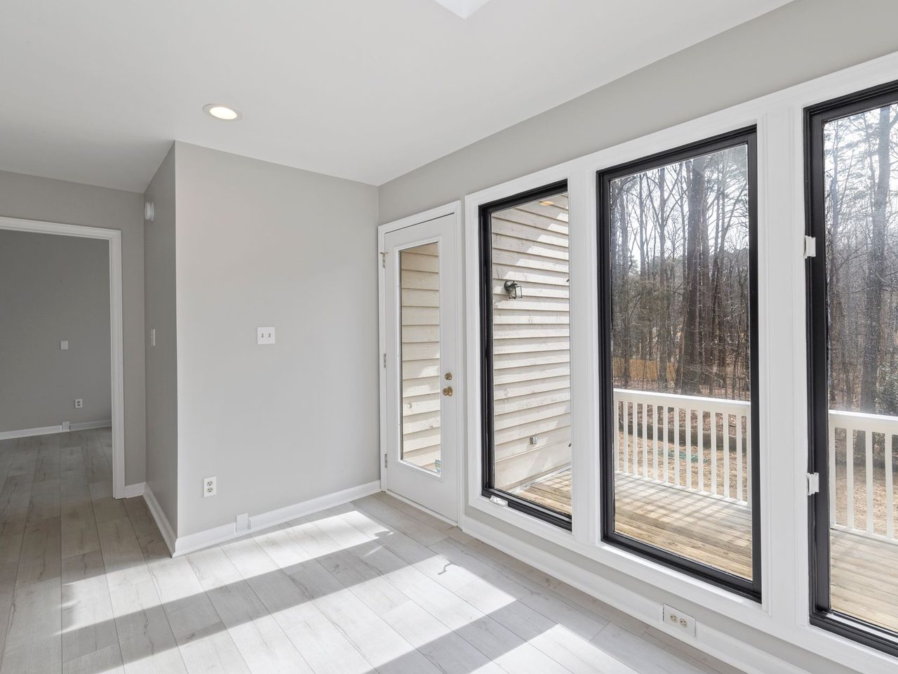 Bright room with tall black-framed glass doors and windows over a light floor
