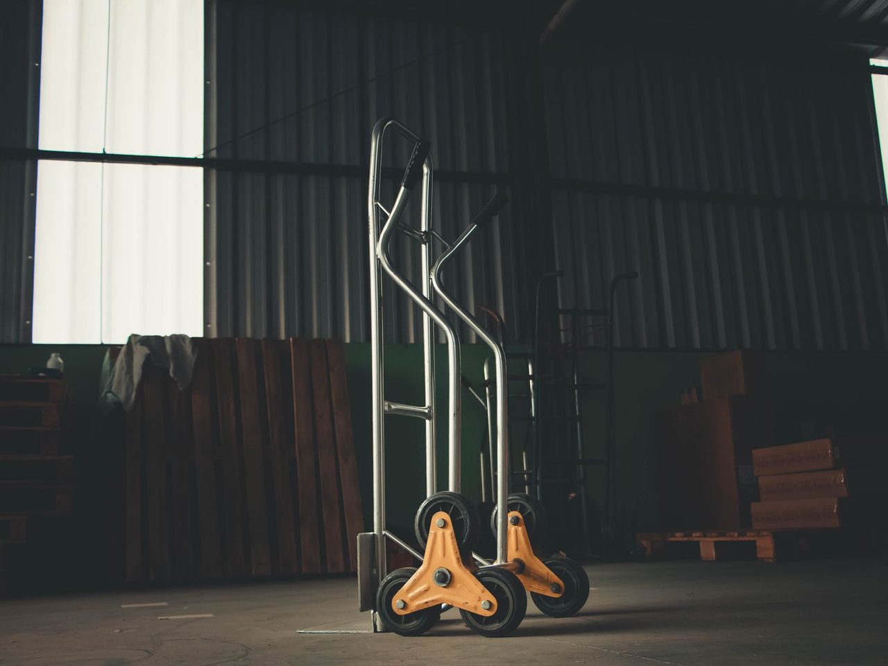 Metal two-wheel hand truck standing in a dim warehouse