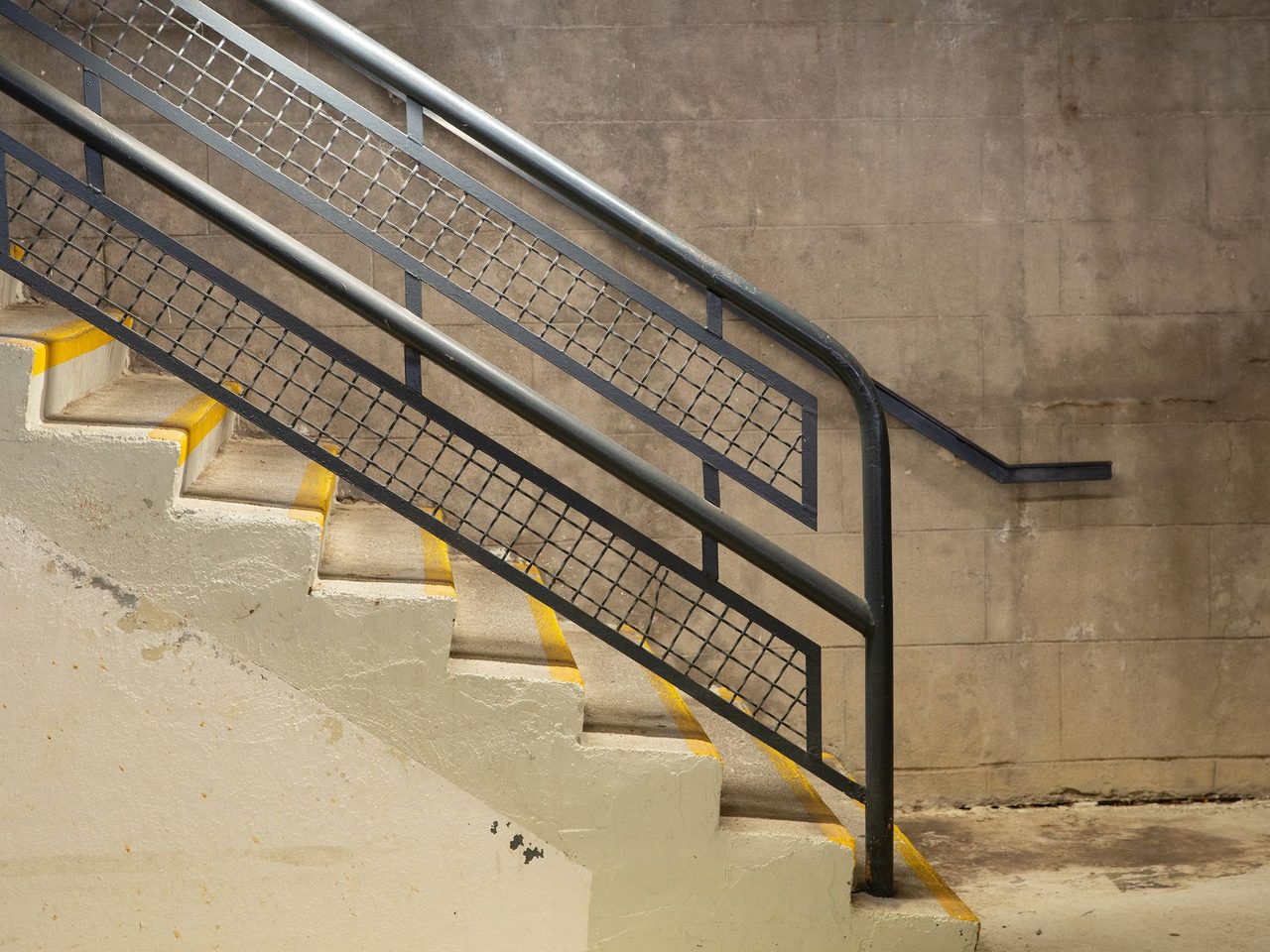 Concrete staircase with yellow stripes on the nosings and metal handrails