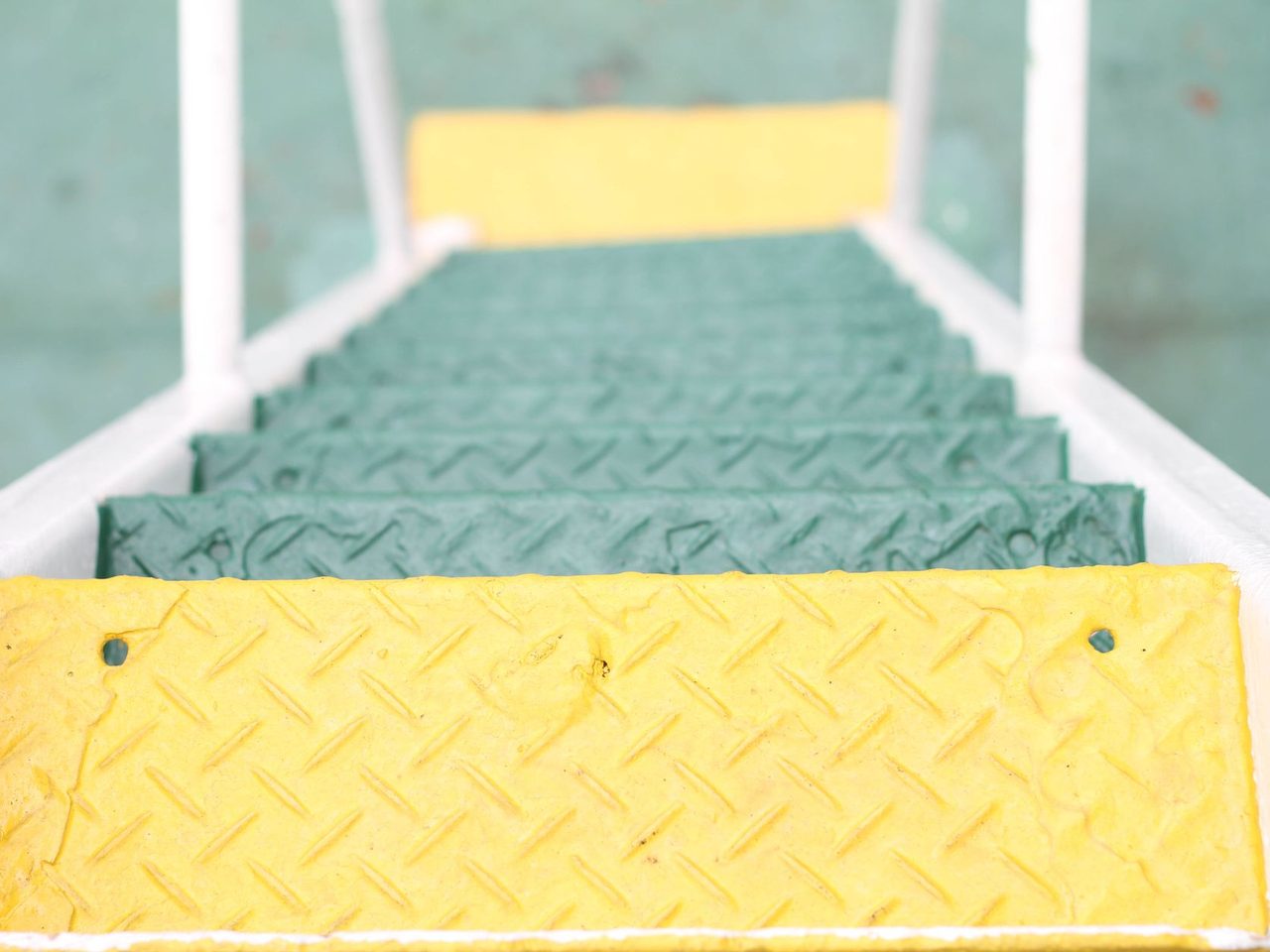 Metal stairs with a diamond pattern and yellow treads at top and bottom