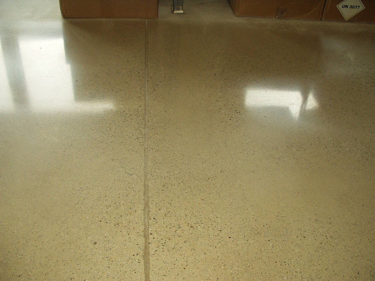 Close-up of a polished concrete floor with speckled aggregate and a straight saw-cut joint