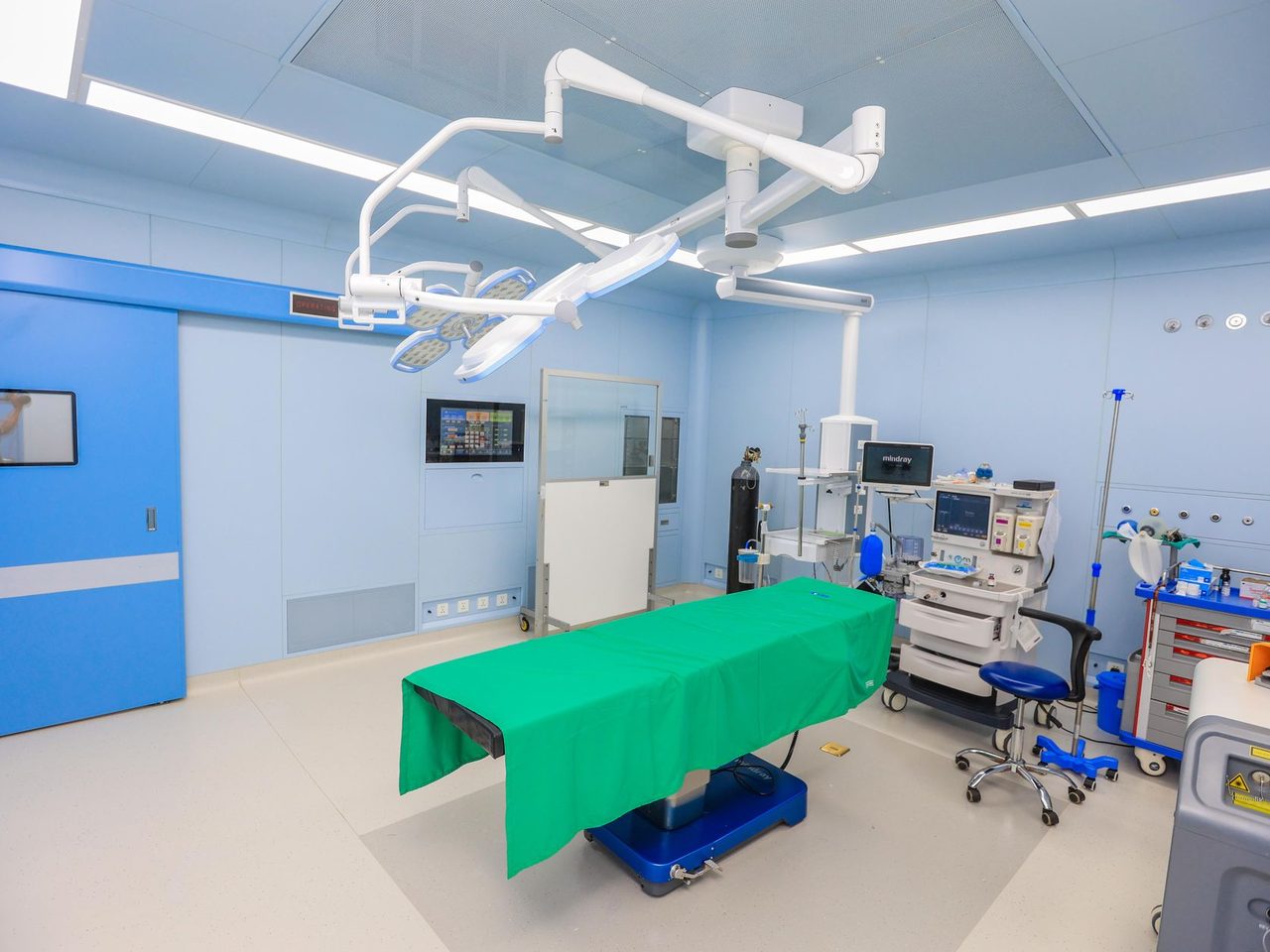 Operating room with blue walls, surgical lights and a light floor