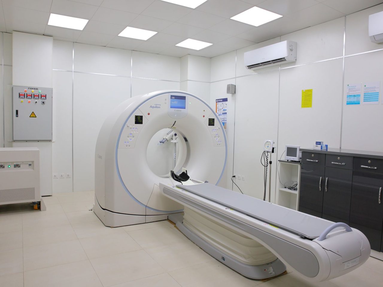 Hospital imaging room with a CT scanner, a light floor and dark cabinets