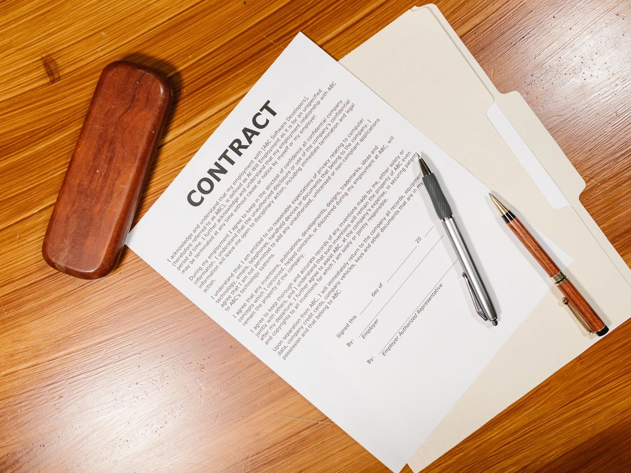 Contract document on a wooden desk with two pens