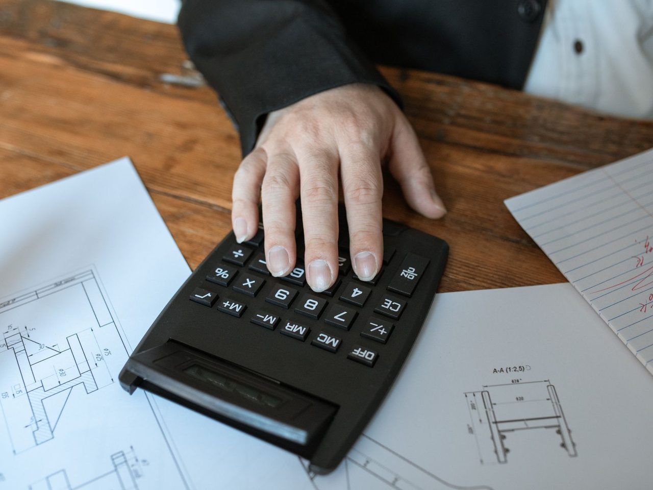 Hand using a calculator on top of architectural drawings