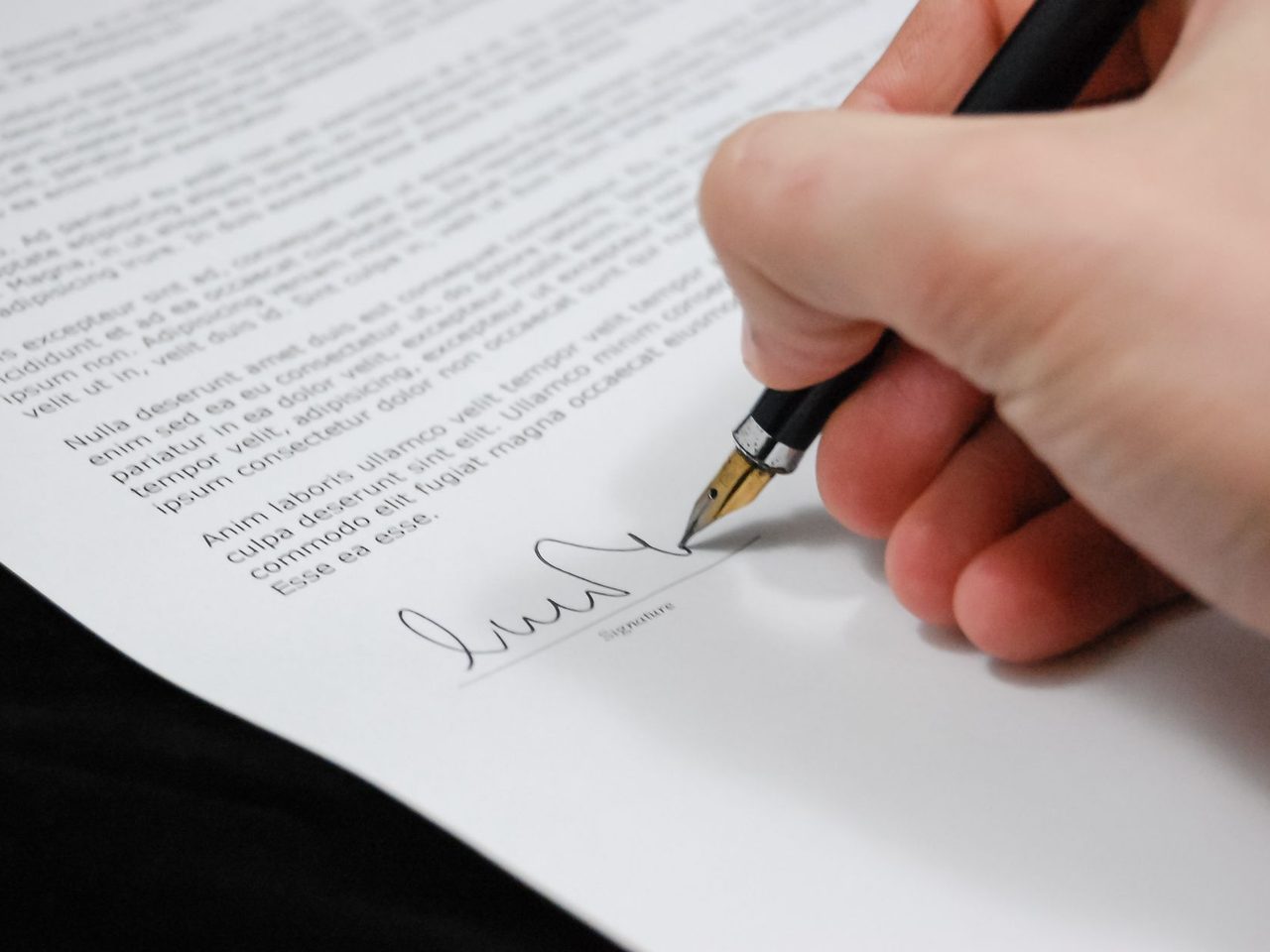 Close-up of a hand signing a document with a fountain pen