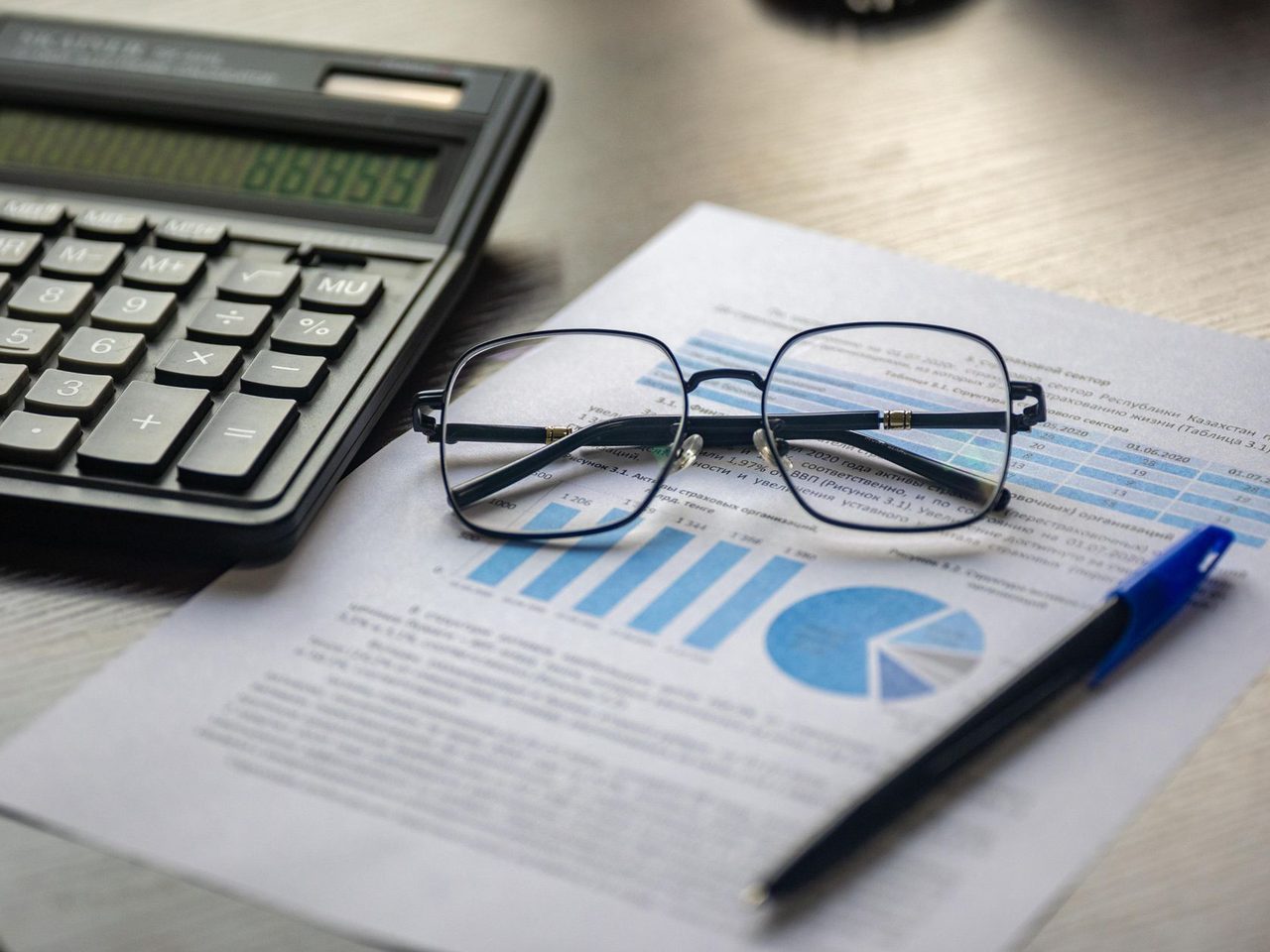 Calculator, glasses and a pen on a printed report