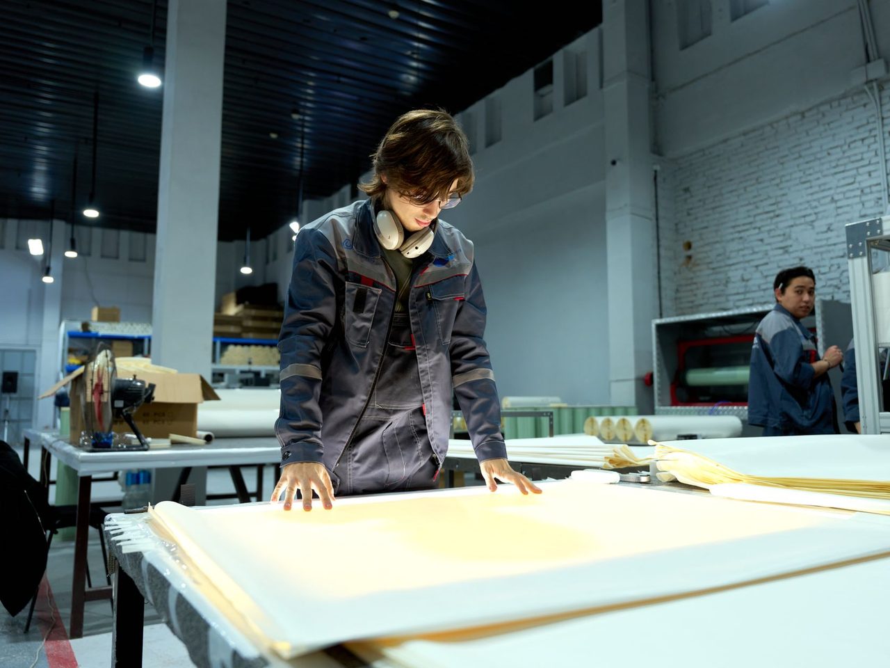 Worker checking large sheets of material on a table in a factory