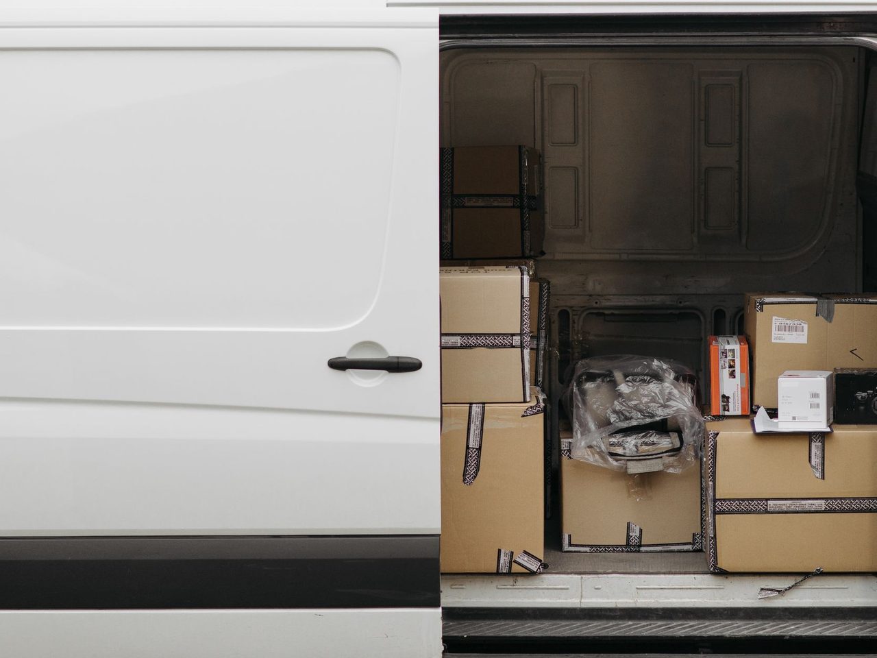 Open side door of a white delivery van loaded with boxes