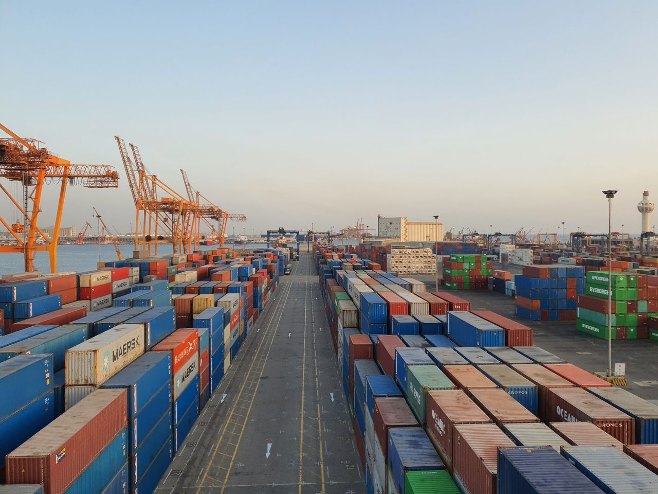 Rows of stacked shipping containers at a port at sunrise