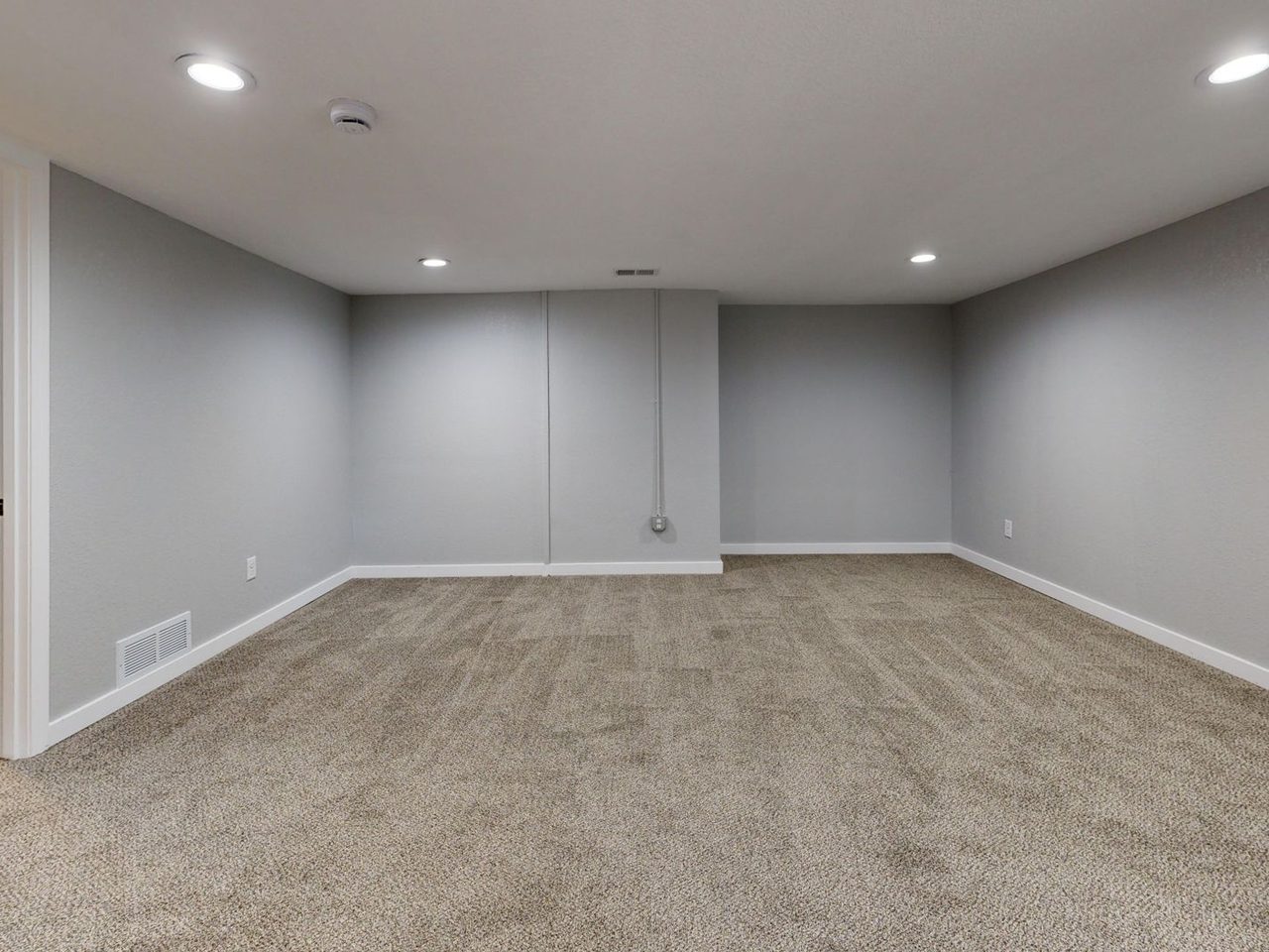 Empty basement room with gray walls and carpet