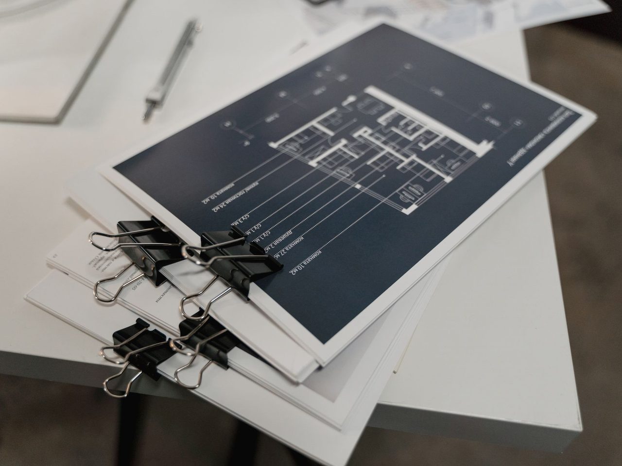 Stack of architectural floor plans held with binder clips