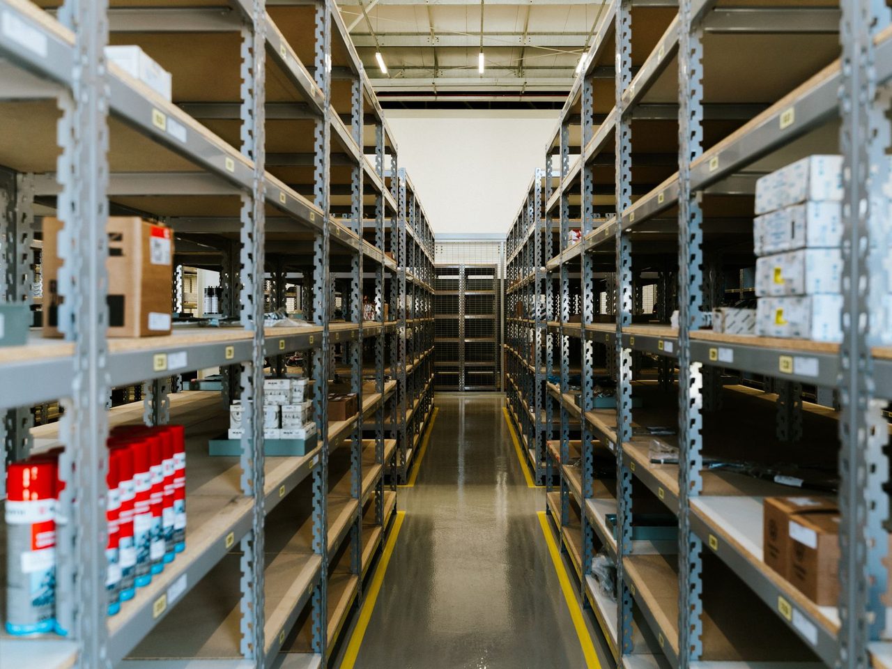 Long warehouse aisle between metal shelving with stored goods