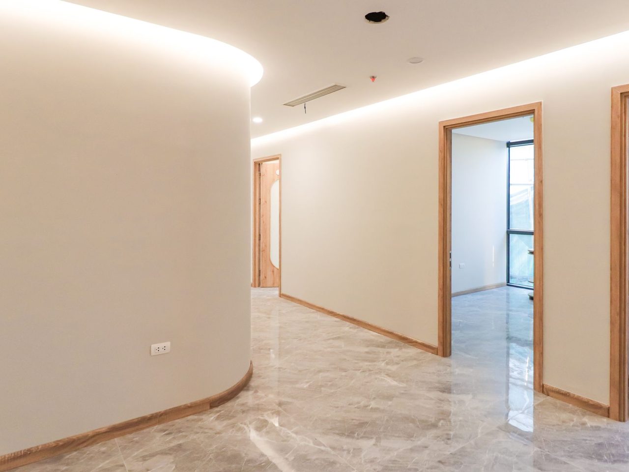 Curved corridor with a stone-look floor and wooden door frames