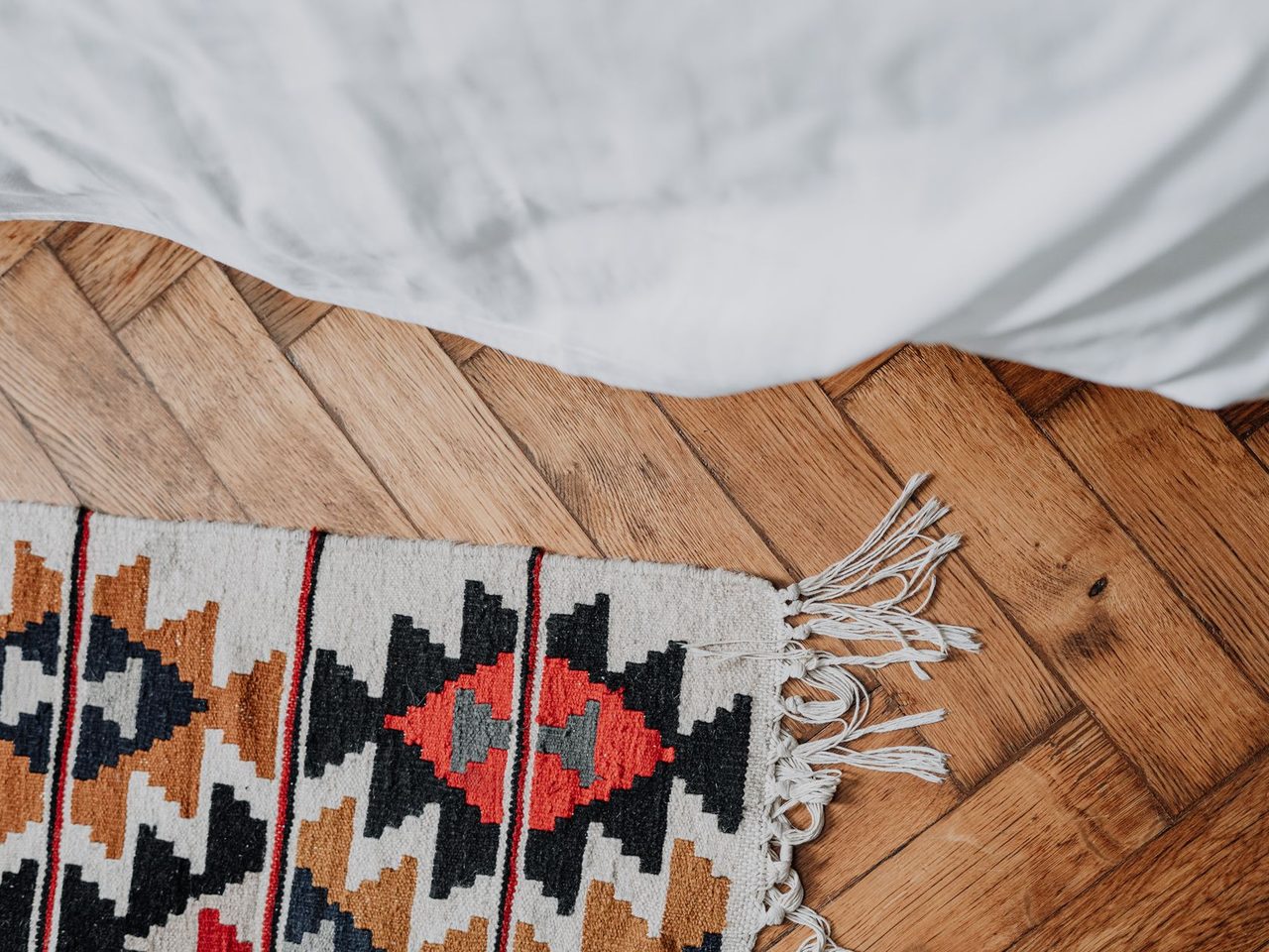 Patterned rug on a chevron-pattern wood floor