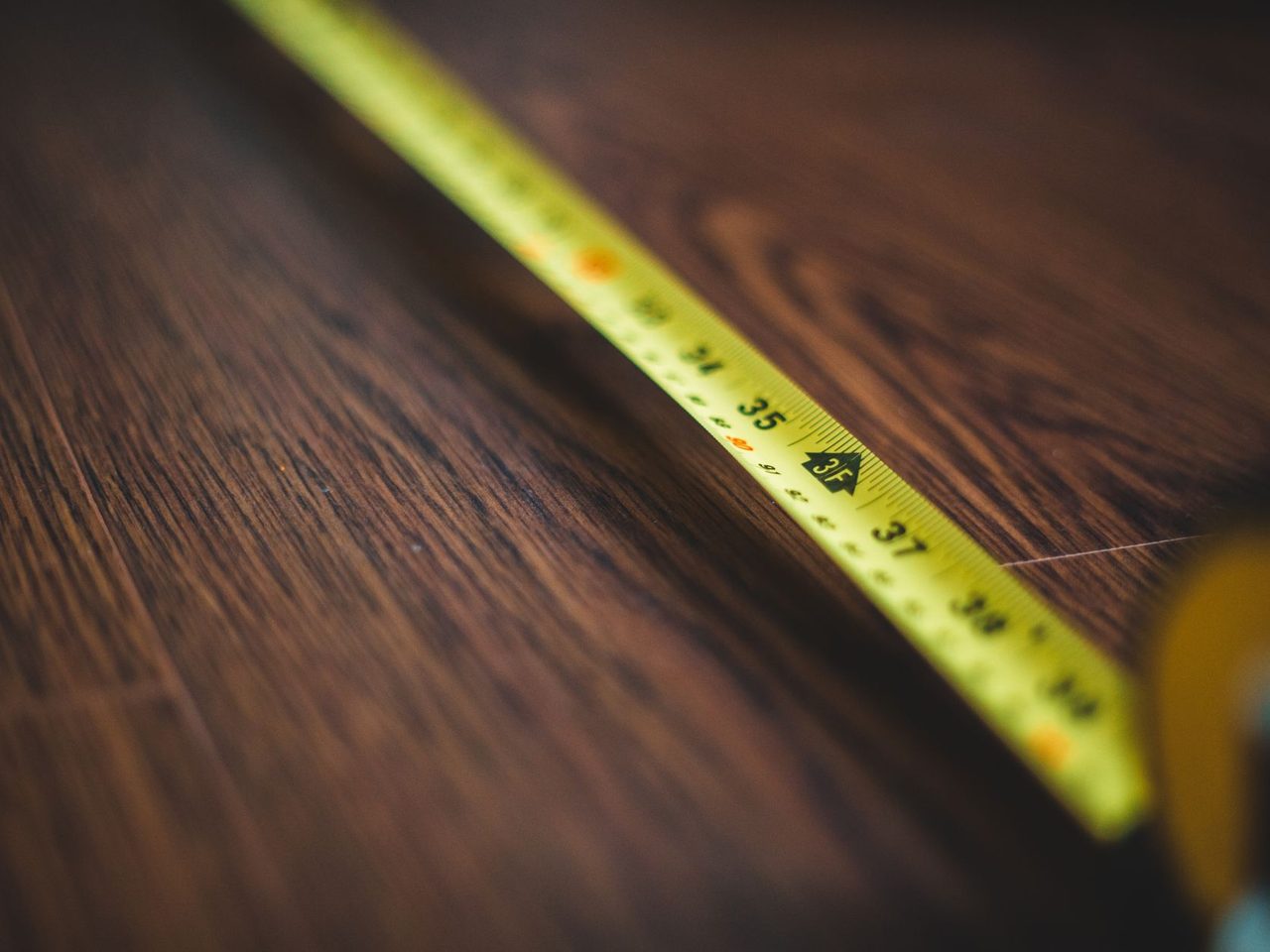 Yellow tape measure extended across a dark wood floor