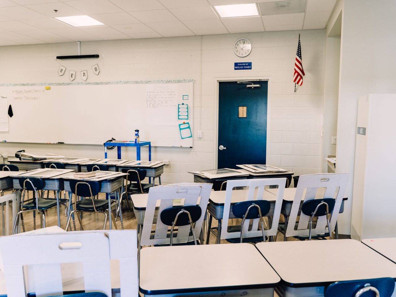 Empty classroom with desks, a whiteboard and a flag