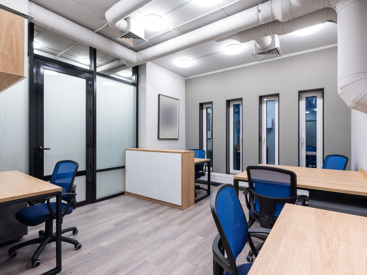 Office with wooden desks, blue chairs and a wood-look floor