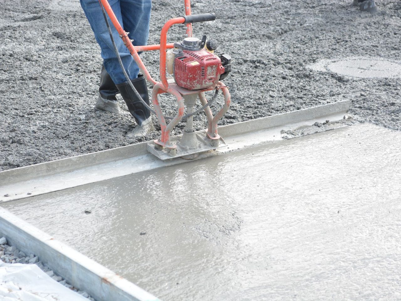 Worker running a power trowel over freshly poured concrete