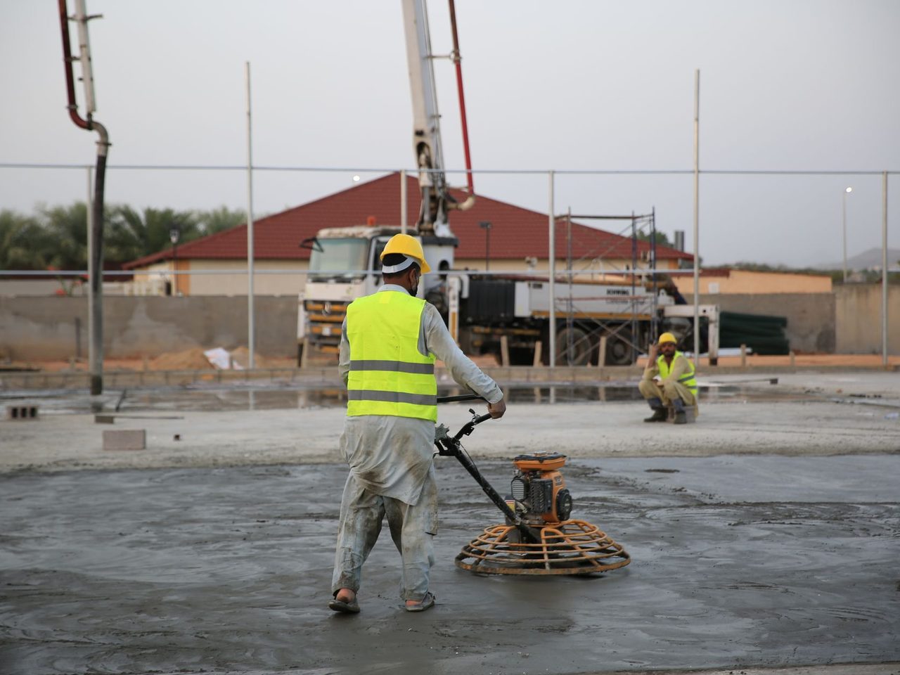 Worker running a power trowel across a freshly poured floor