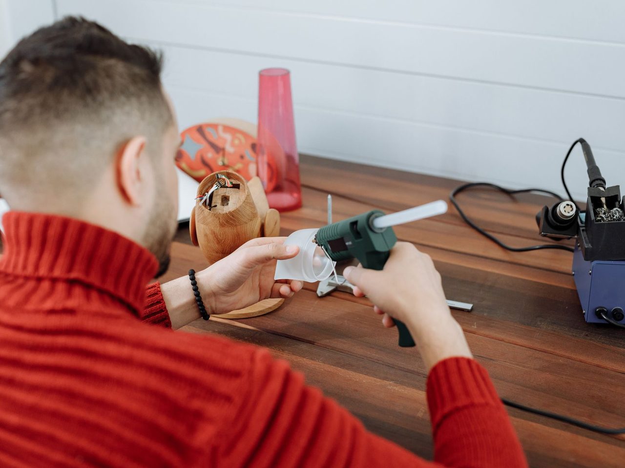 Person using a hot glue gun at a wooden workbench