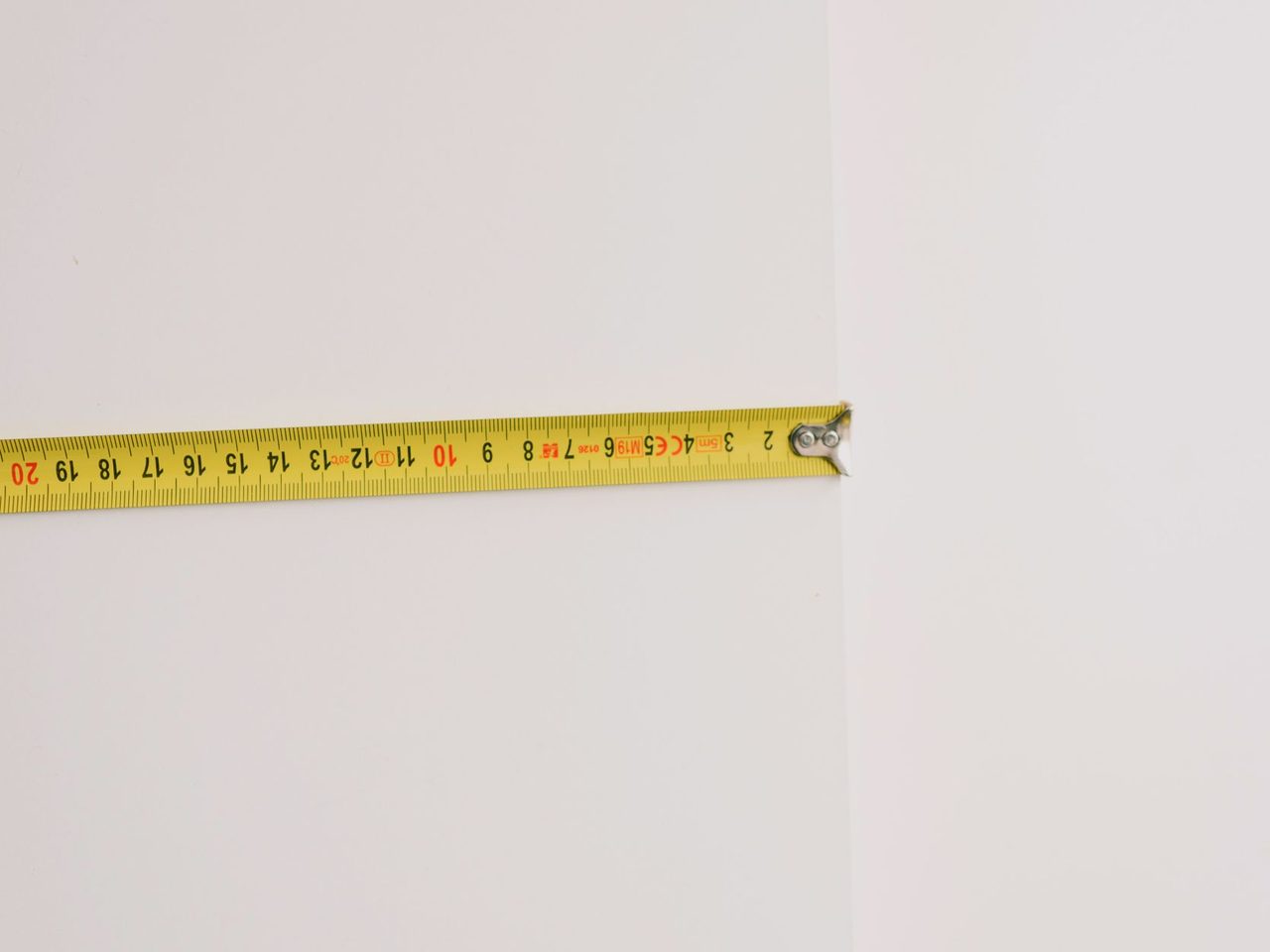 Yellow tape measure held against a bare wall during renovation