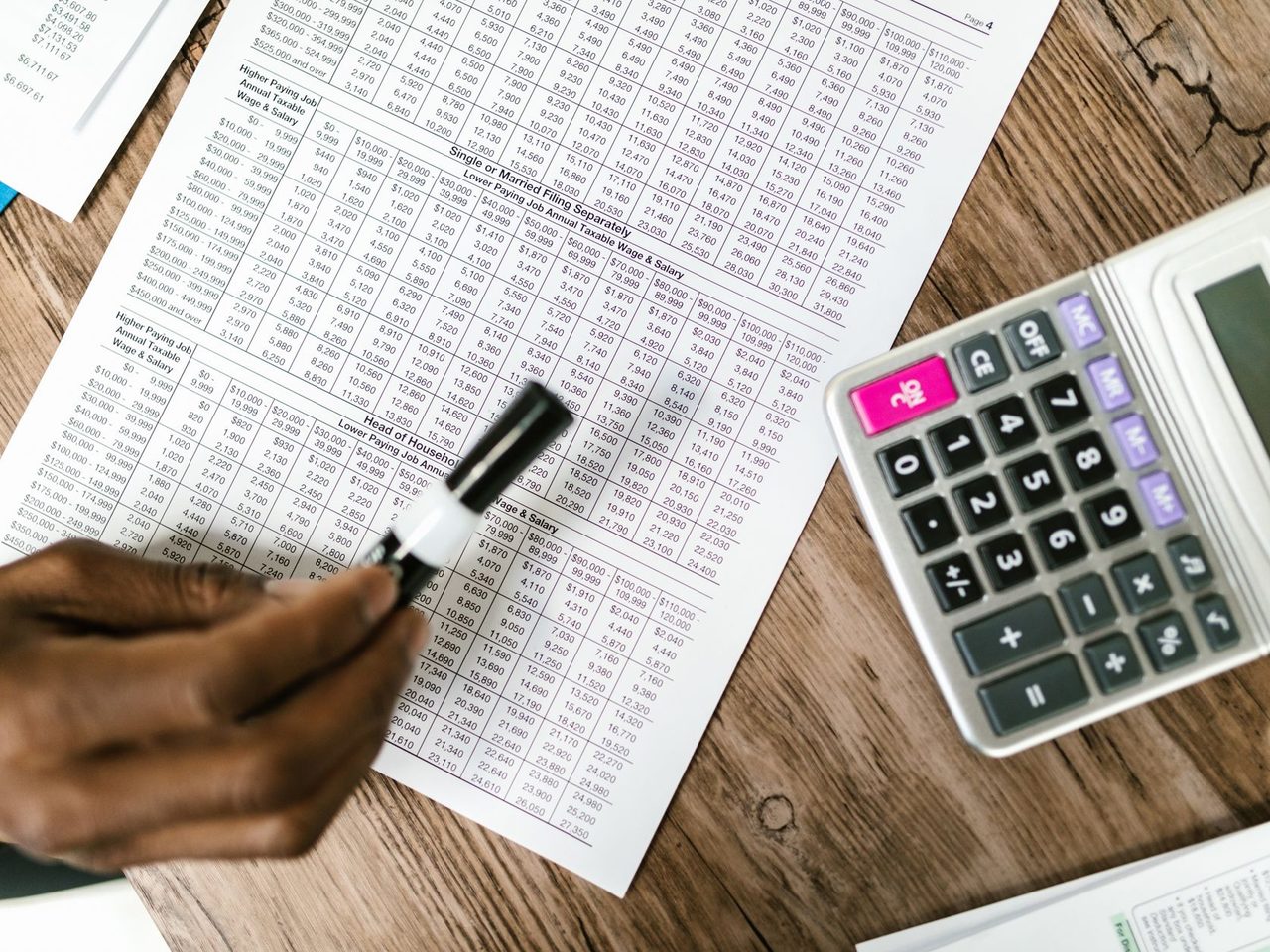 Tax documents, a pen and a calculator on a wooden table