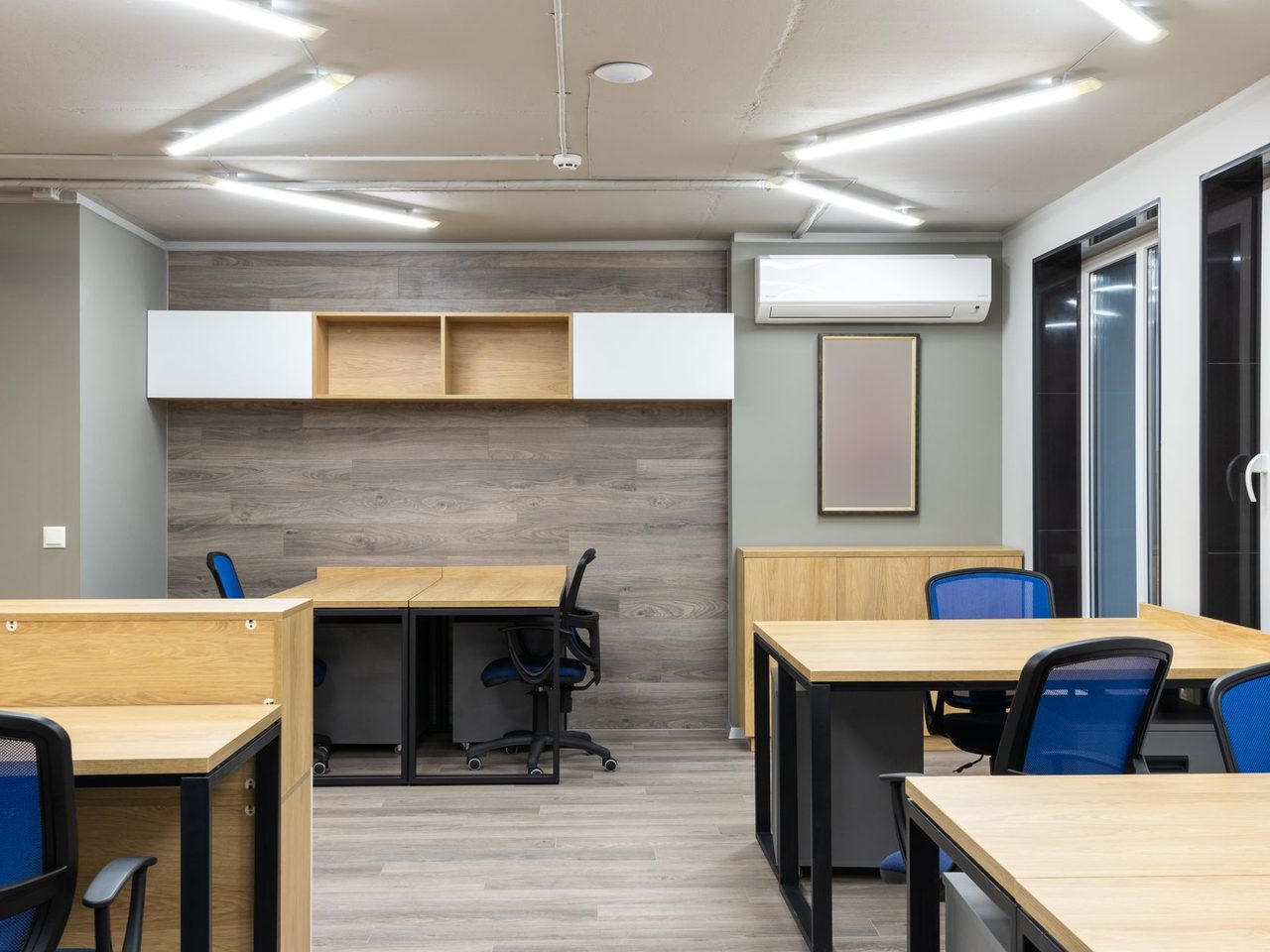 Office with wooden desks and blue chairs on a wood-look floor