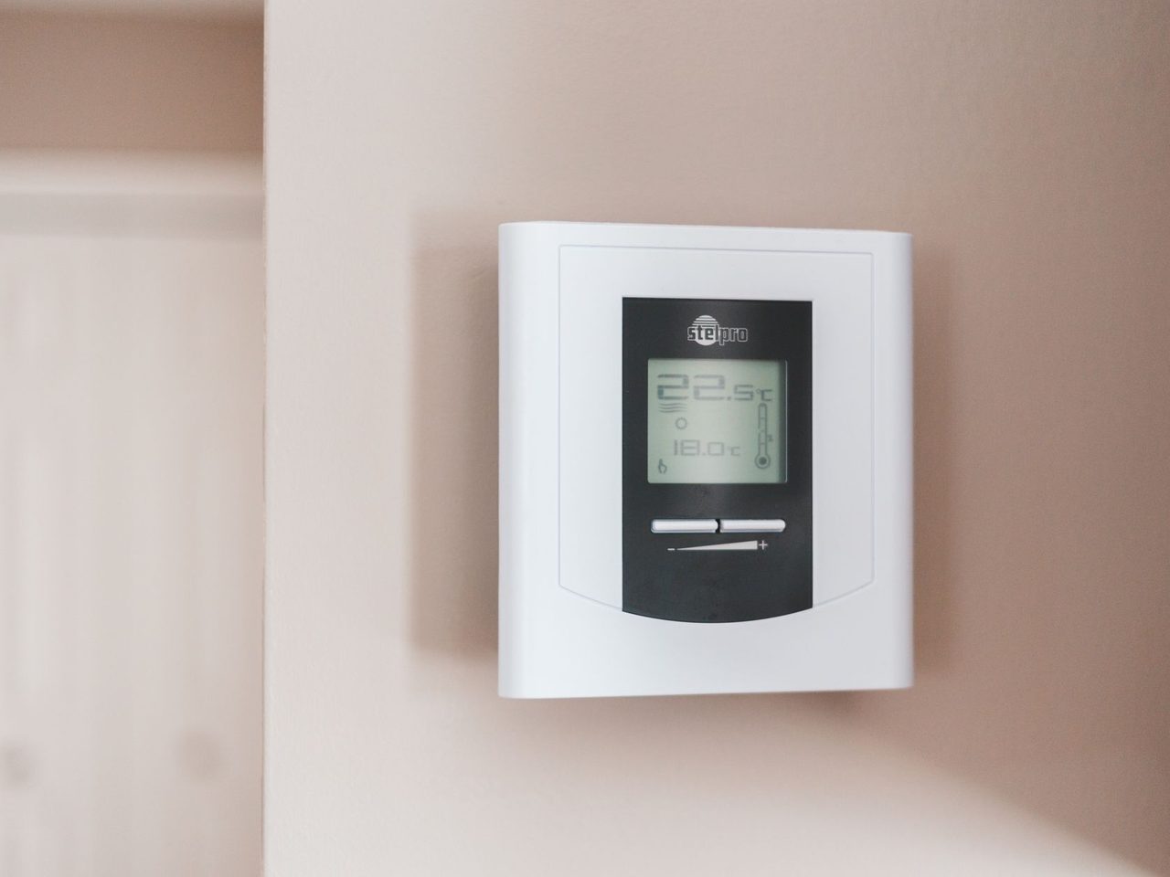 Digital thermostat with a small display mounted on a light wall