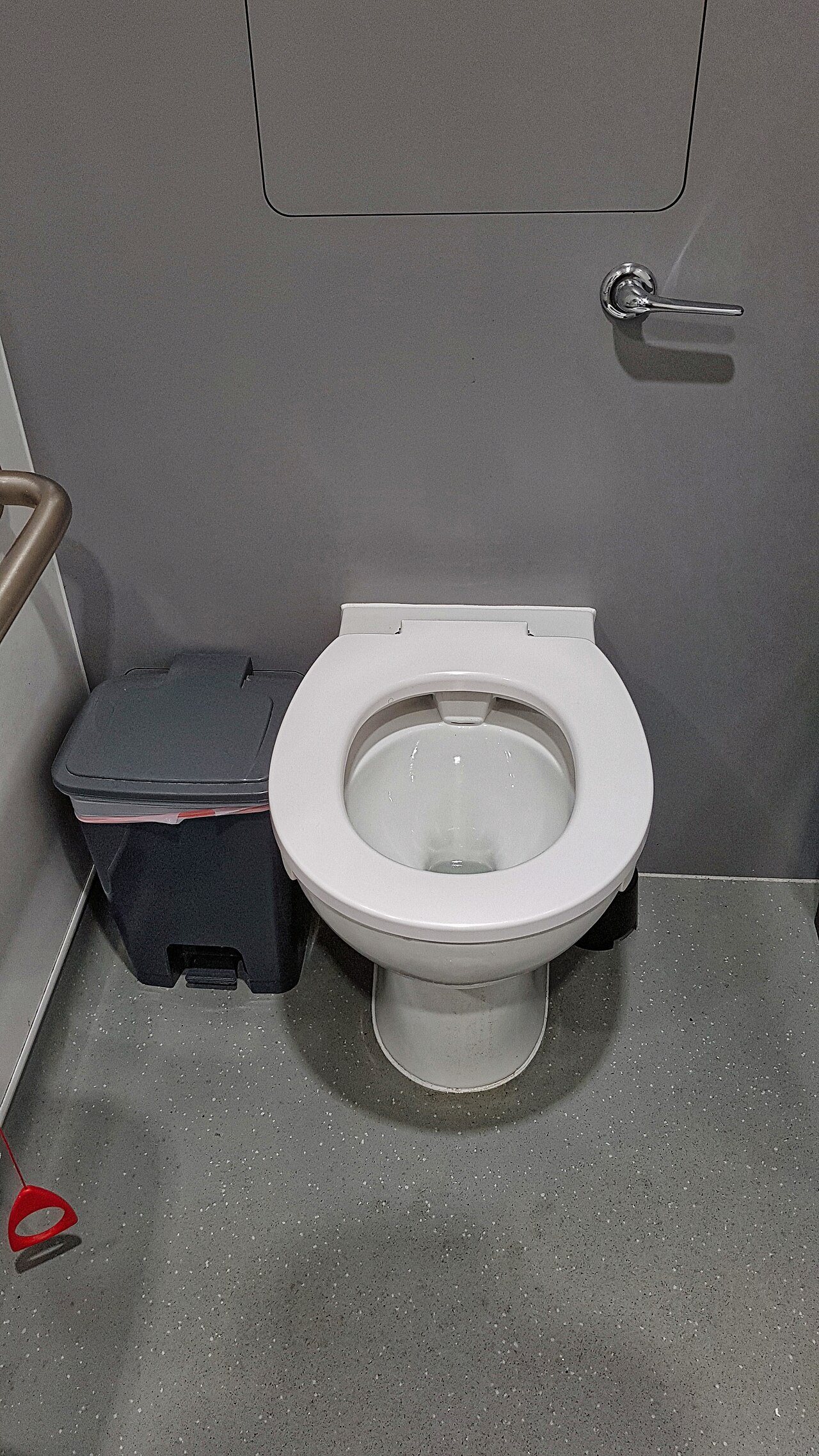 Accessible toilet with grey speckled safety flooring that turns up the wall at the base
