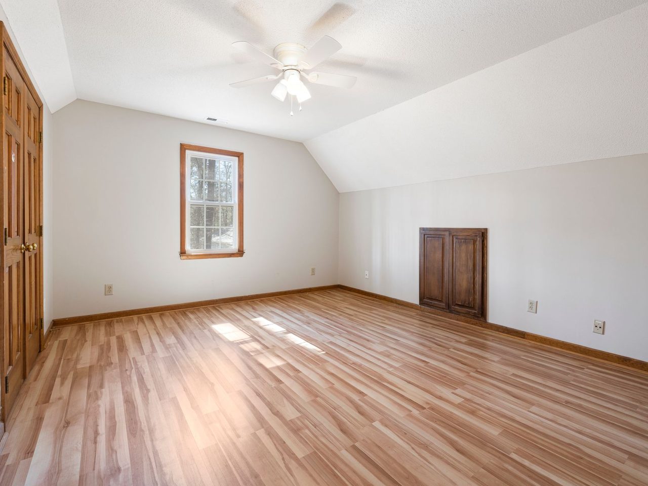 Bright empty room with a glossy honey-toned wood floor and two windows