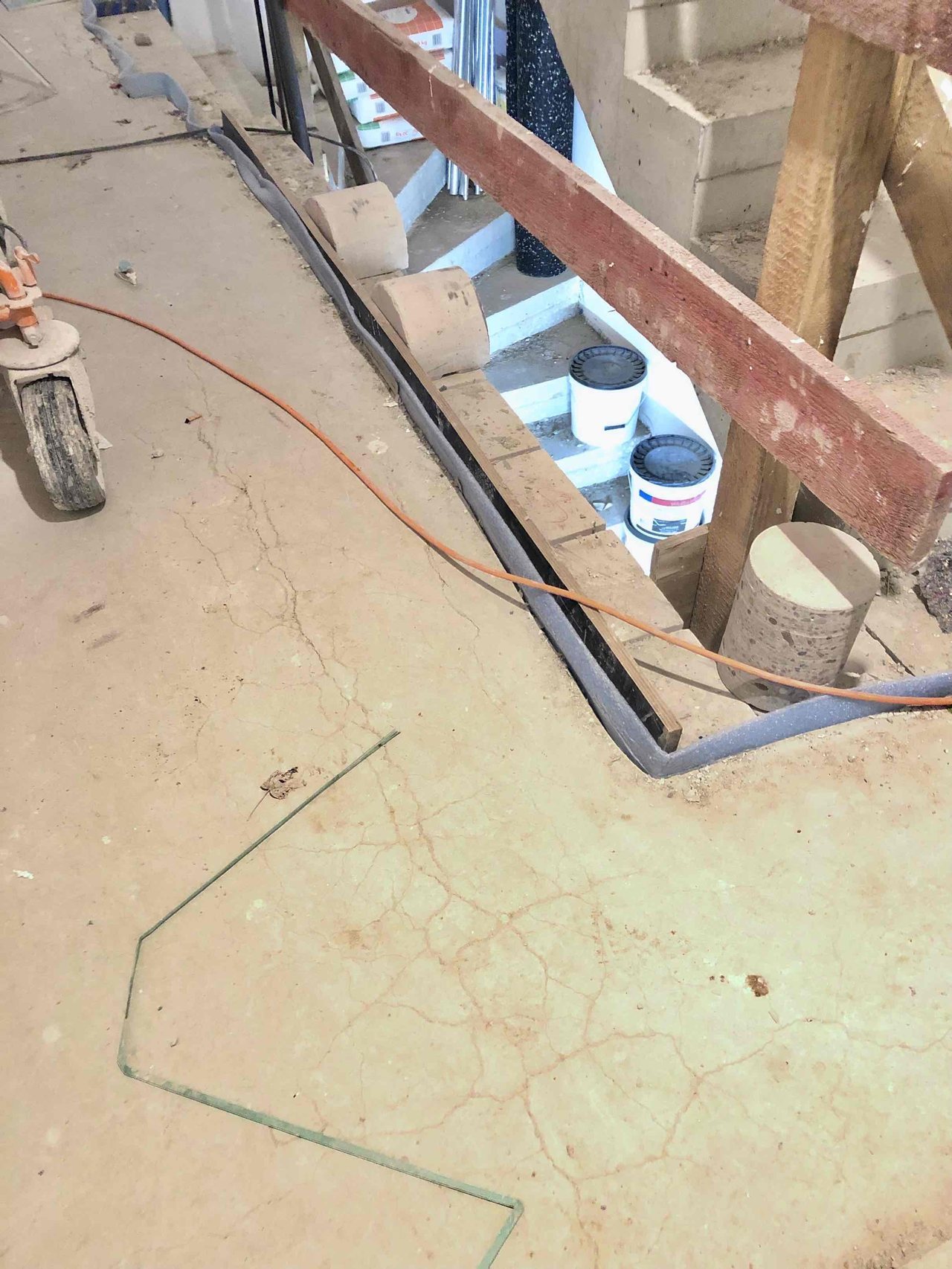 Floating screed floor with fine cracks across its surface next to an edge strip and a staircase opening