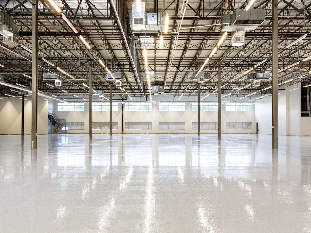 Empty warehouse with a polished concrete floor and a high steel roof structure