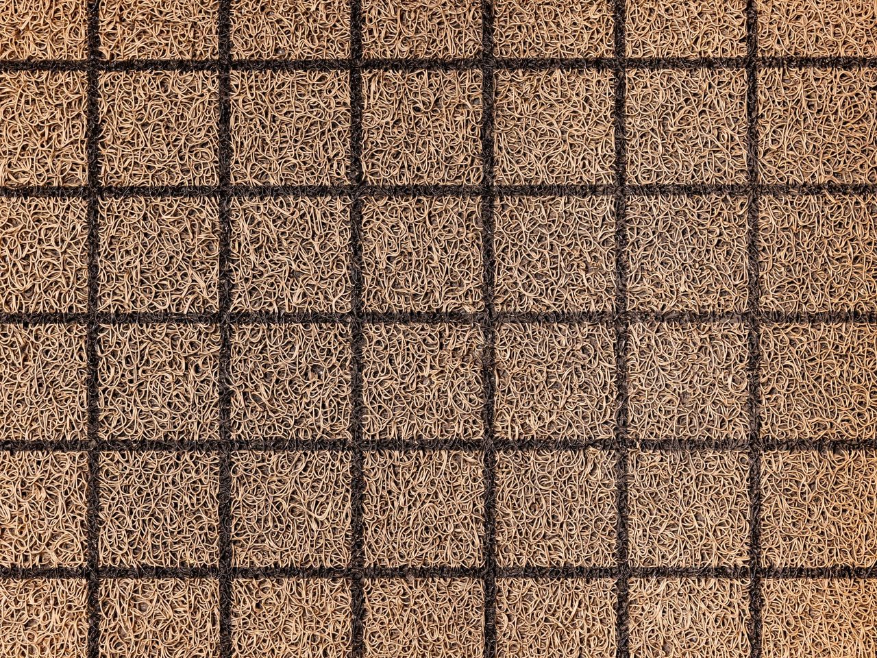 Close-up of a woven coir doormat with a grid pattern